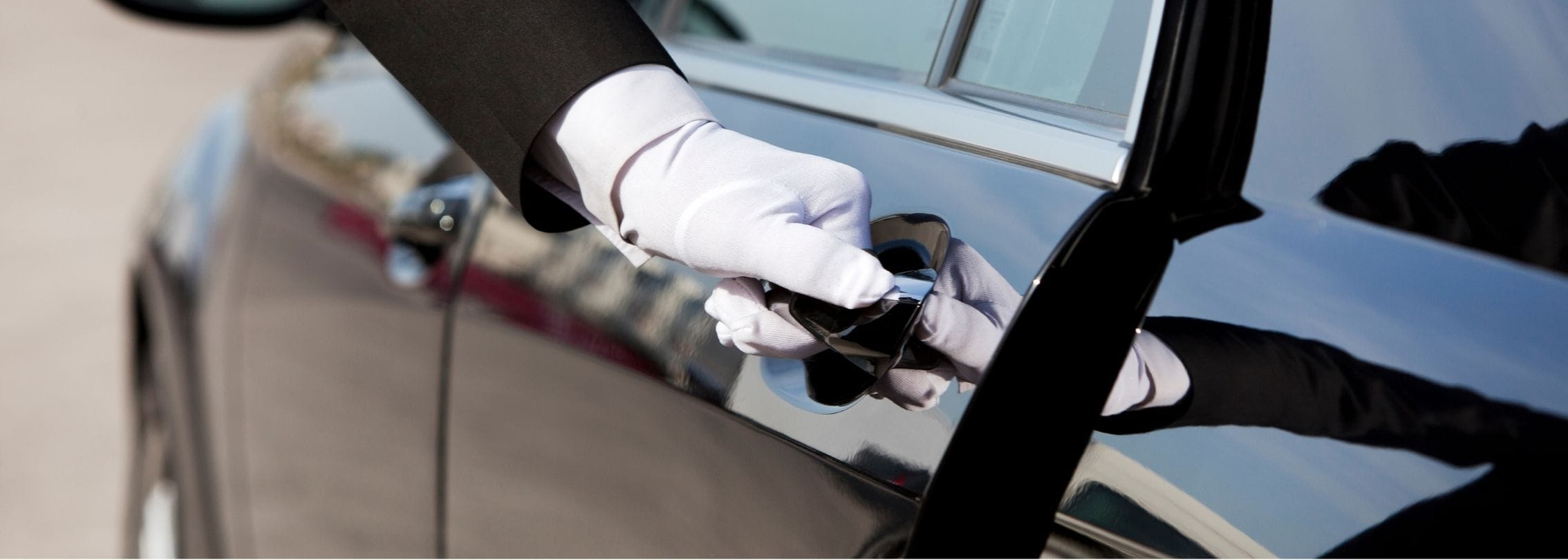 professional chauffeur opening a car door for a VIP client during an airport transfer in Manchester