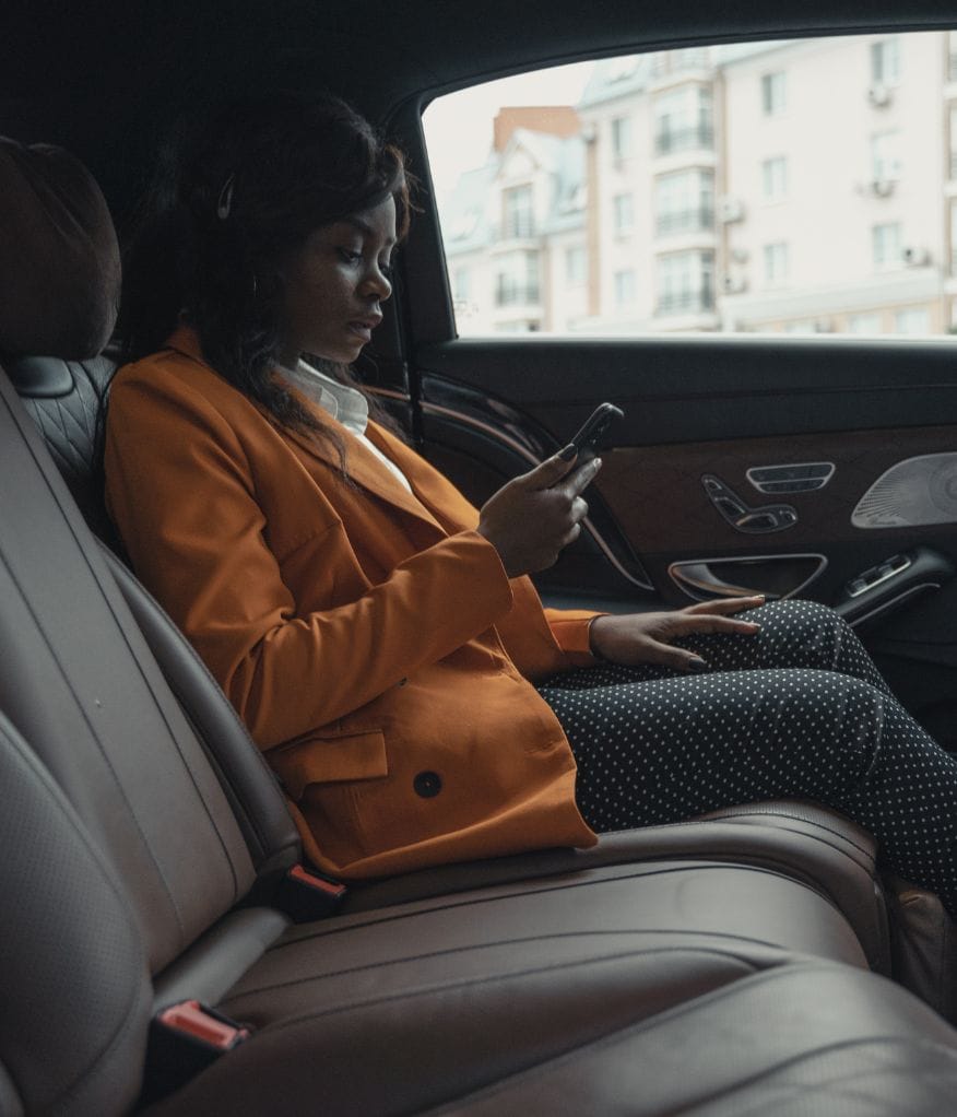 Client using their phone inside a premium chauffeur vehicle