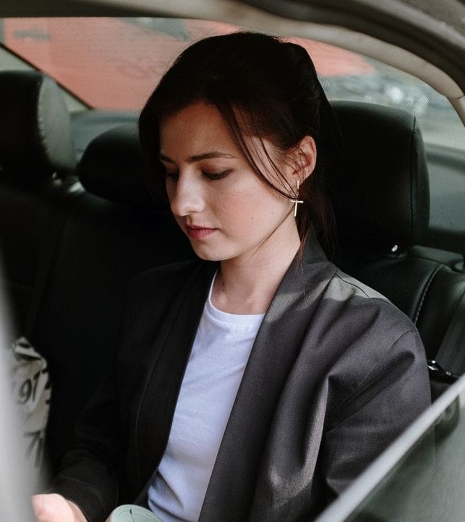 A person checking their phone inside a luxury chauffeur vehicle