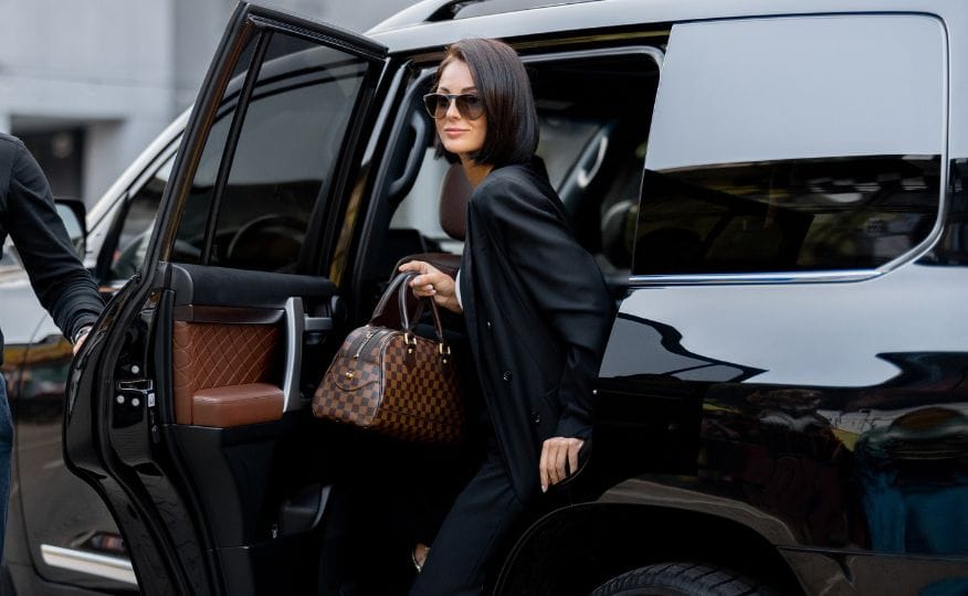 High-profile client stepping out of a luxury car with the door held open by the chauffeur
