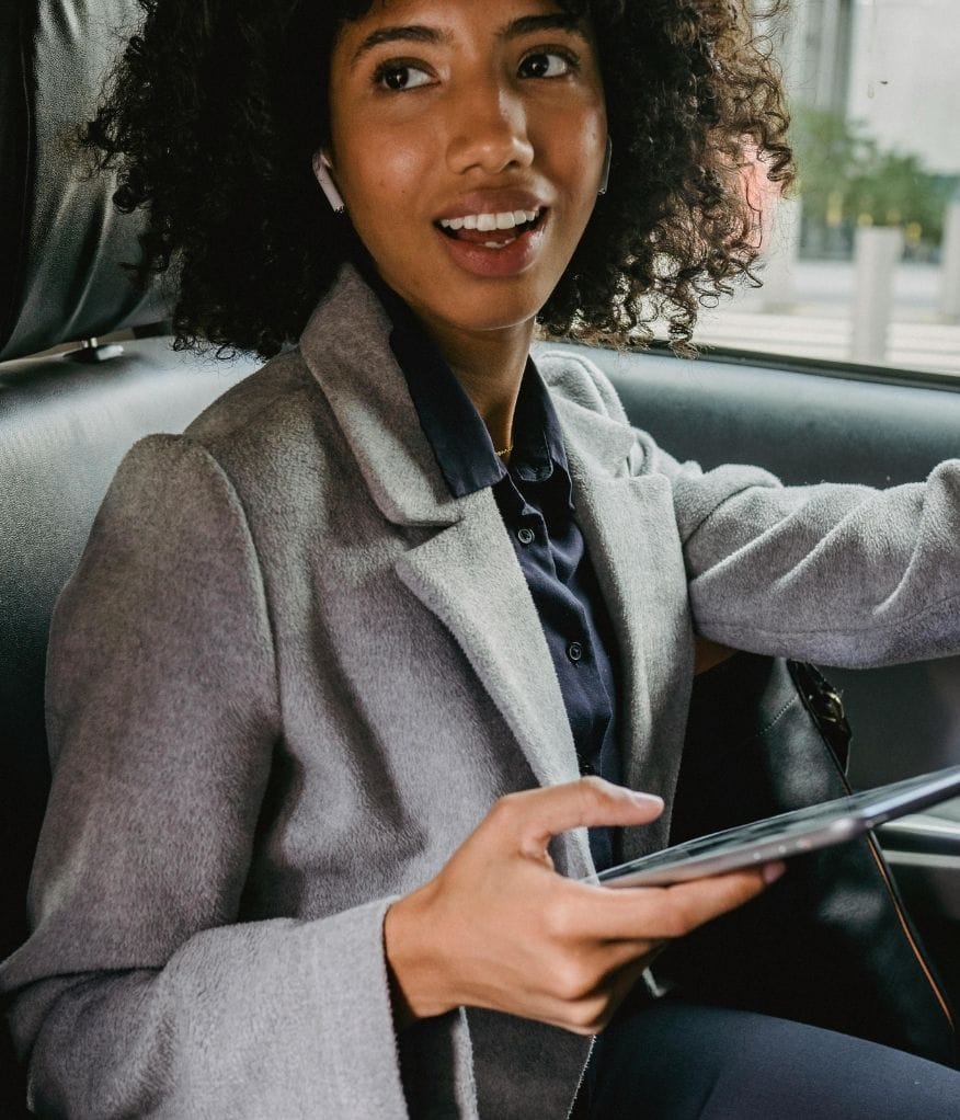 Client using their phone and smiling inside a chauffeur vehicle