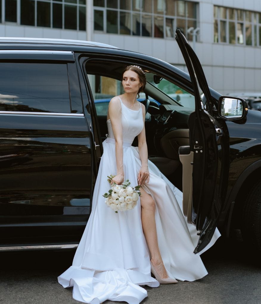 Bride holding her bouquet as she exits a luxury executive van