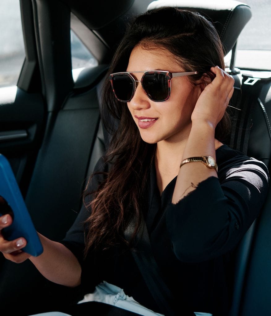 A woman smiling inside a chauffeur vehicle