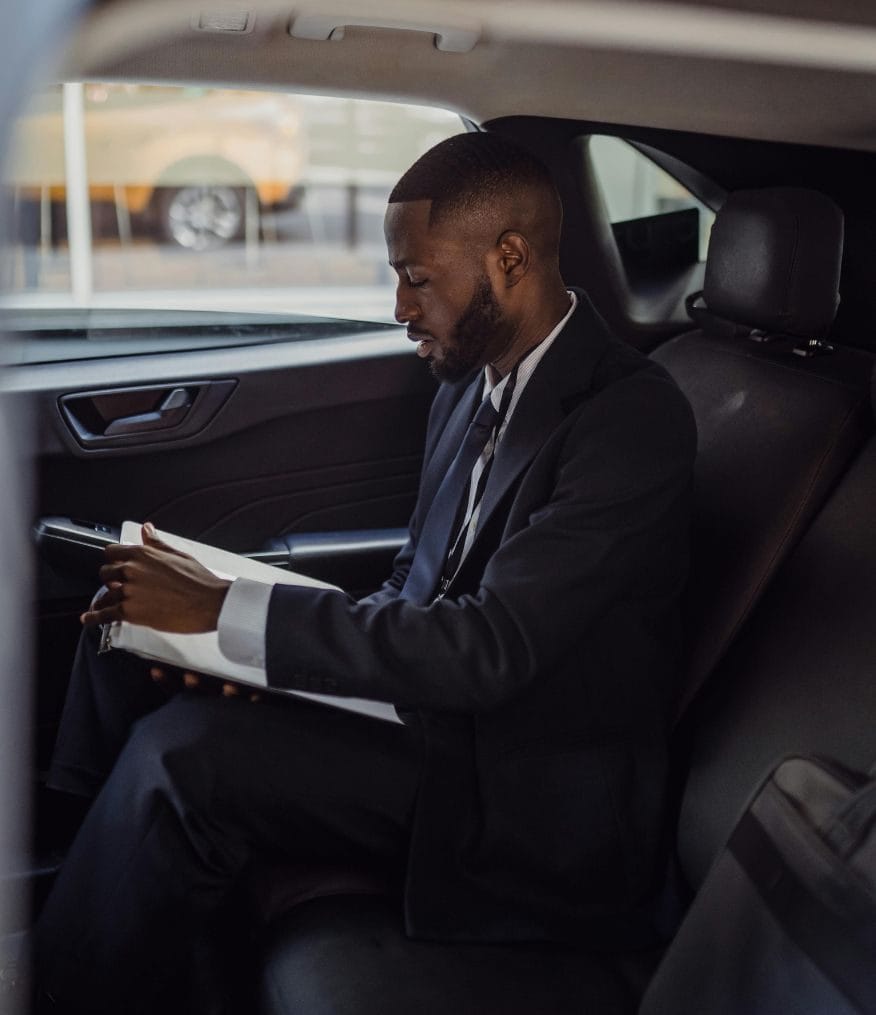 A man reading paperwork inside a chauffeur vehicle