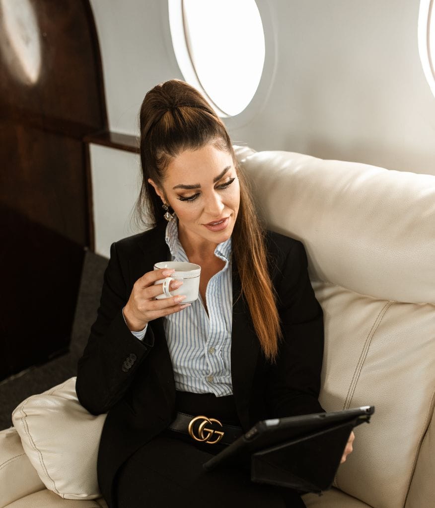 A woman holding a cup and working in a private jet