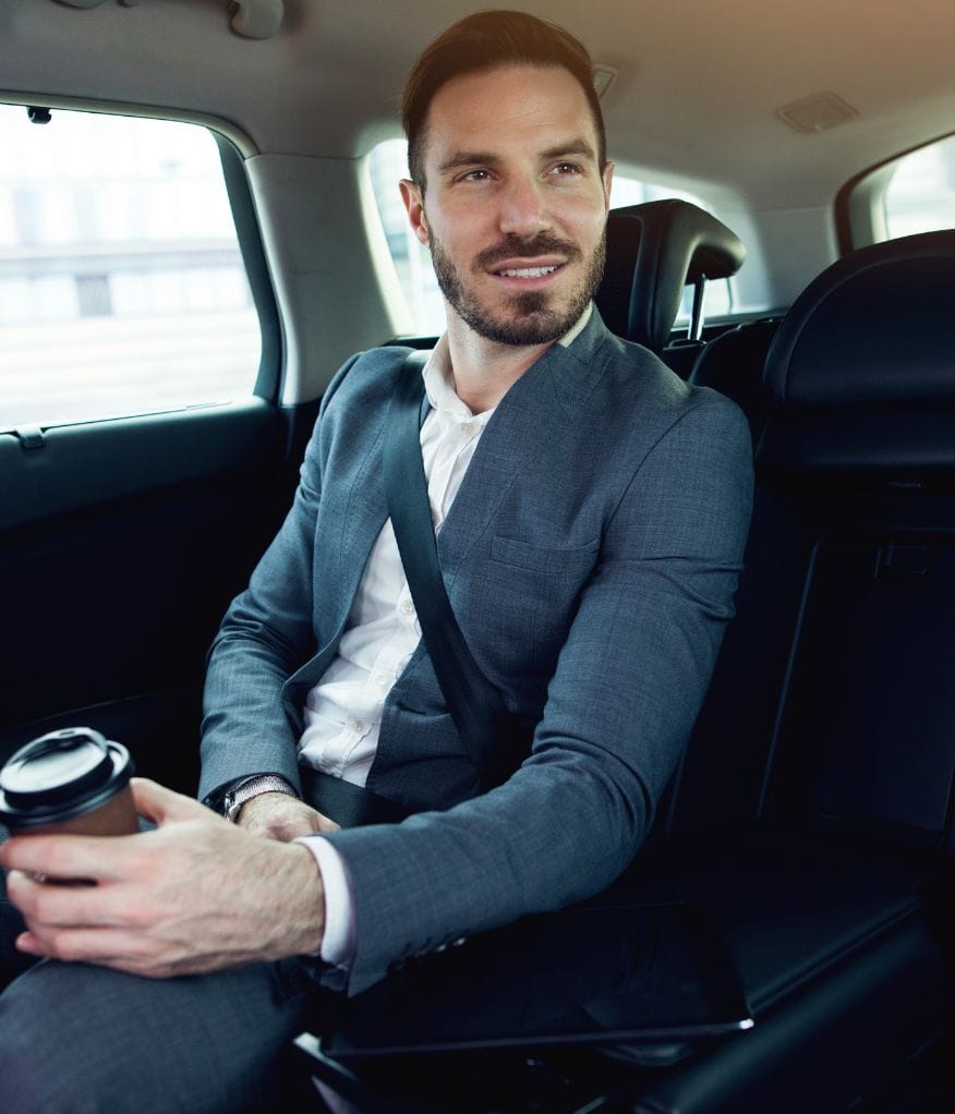 A man holding a coffee cup while in a chauffeur vehicle