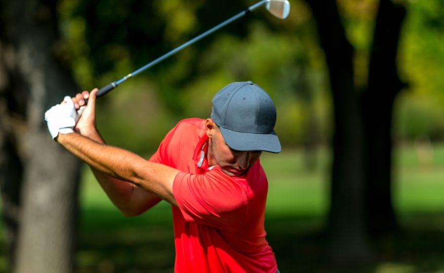 A golf player mid swing