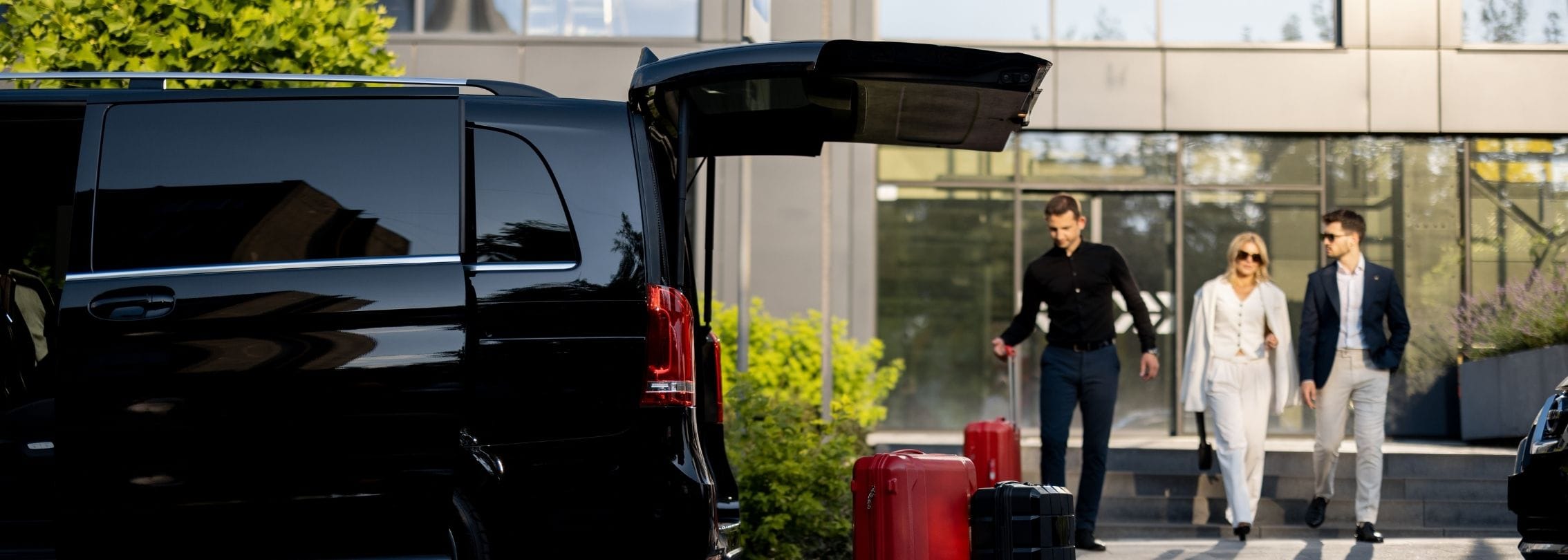 Uniformed chauffeur carefully handling and loading VIP clients’ luggage into a luxury car